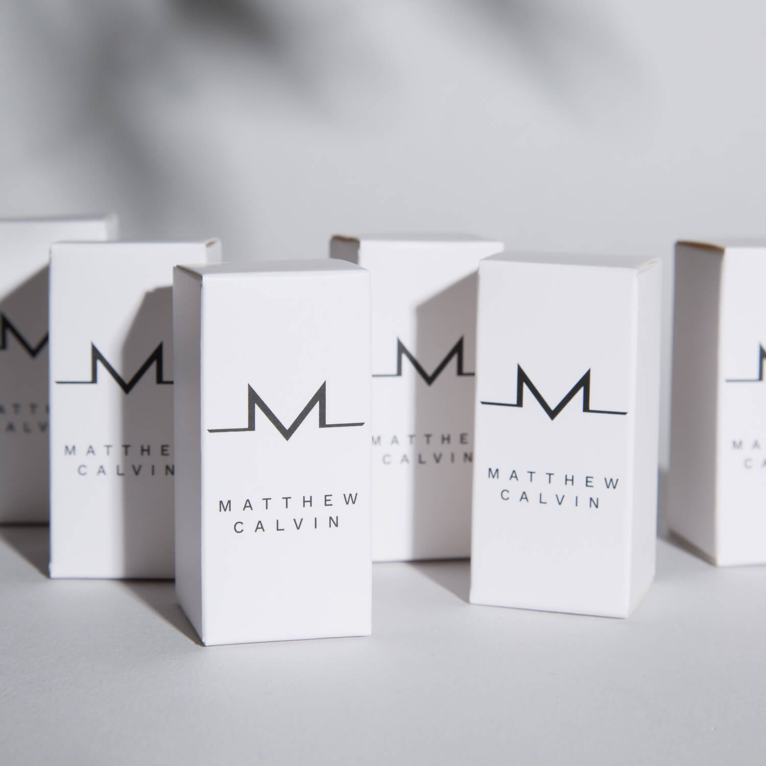 A group of white jewellery packaging with black Matthew Calvin branding