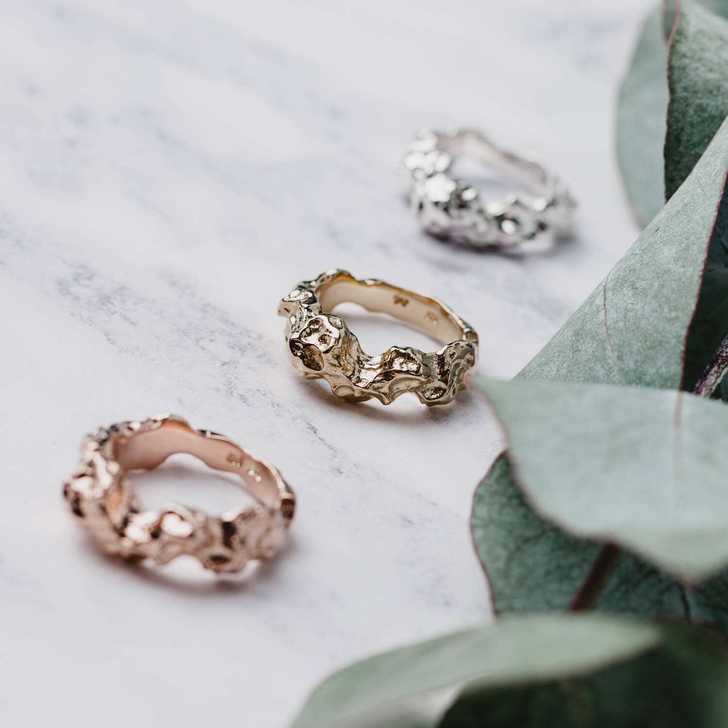 Three rings next to each other, one in silver, one in gold and one in rose gold