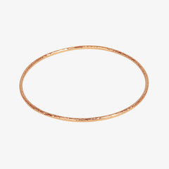 Thin rose gold bangle with meteorite style rough texturing