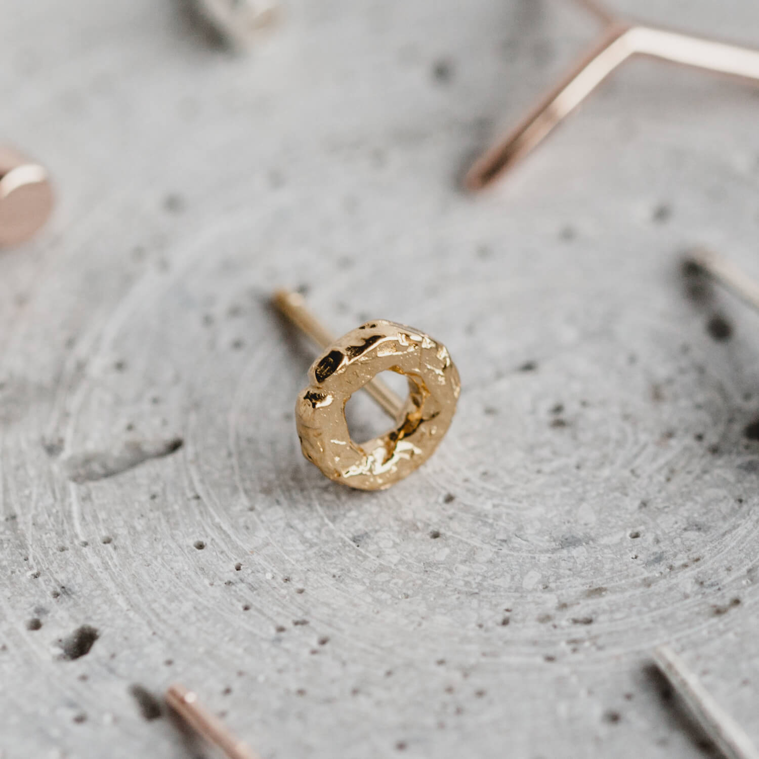 Close up of one round textured earring in rose gold