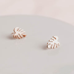 rose gold monstera leaf shaped earrings by matthew calvin photographed on a grey slate