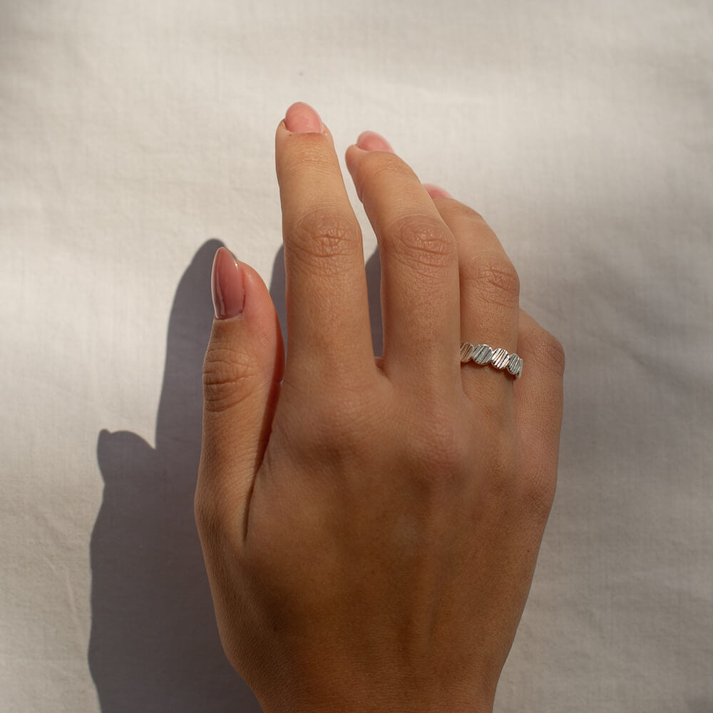A model wearing a silver ring with a textured effect