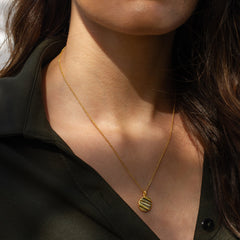 A woman wearing a gold necklace on a belcher chain with textured detail