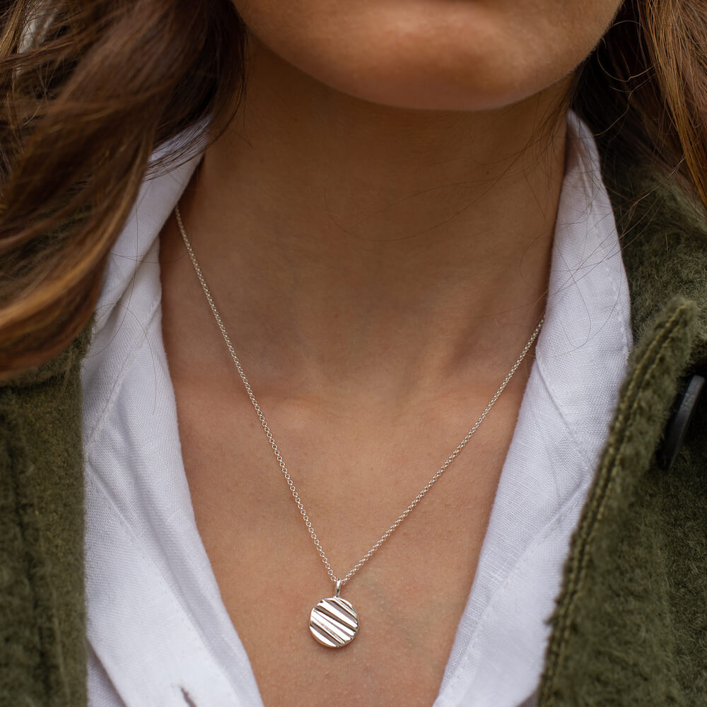 A close up of a woman wearing a textured silver necklace