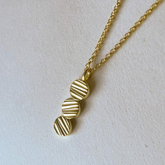 Close up of a gold pendant on a belcher chain
