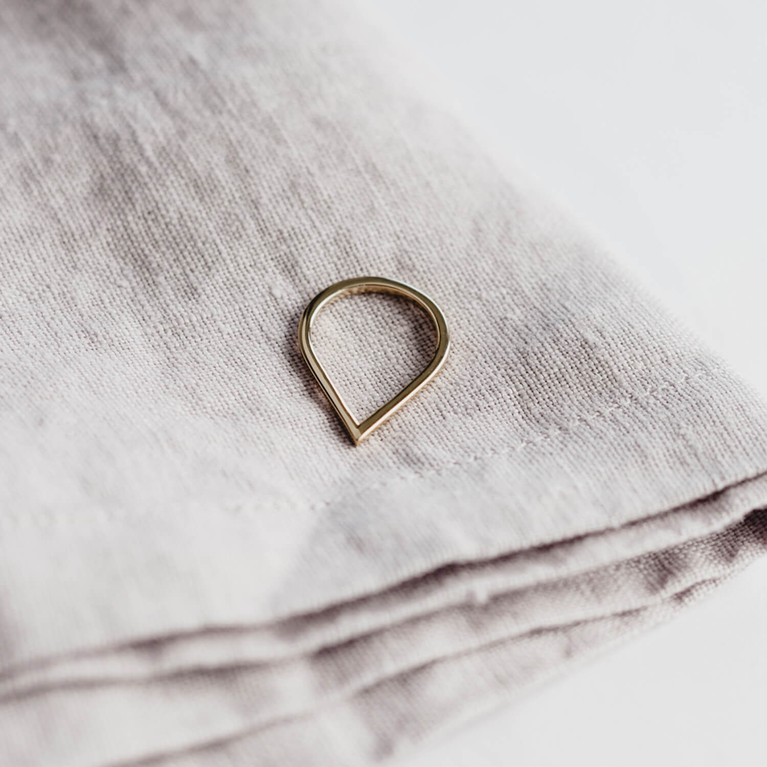 Close up of rose gold Point Ring against a rough cloth bakground
