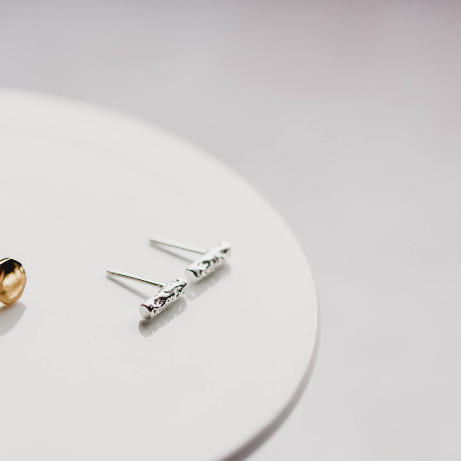 Close up of small bar earrings in silver on a white marble plate