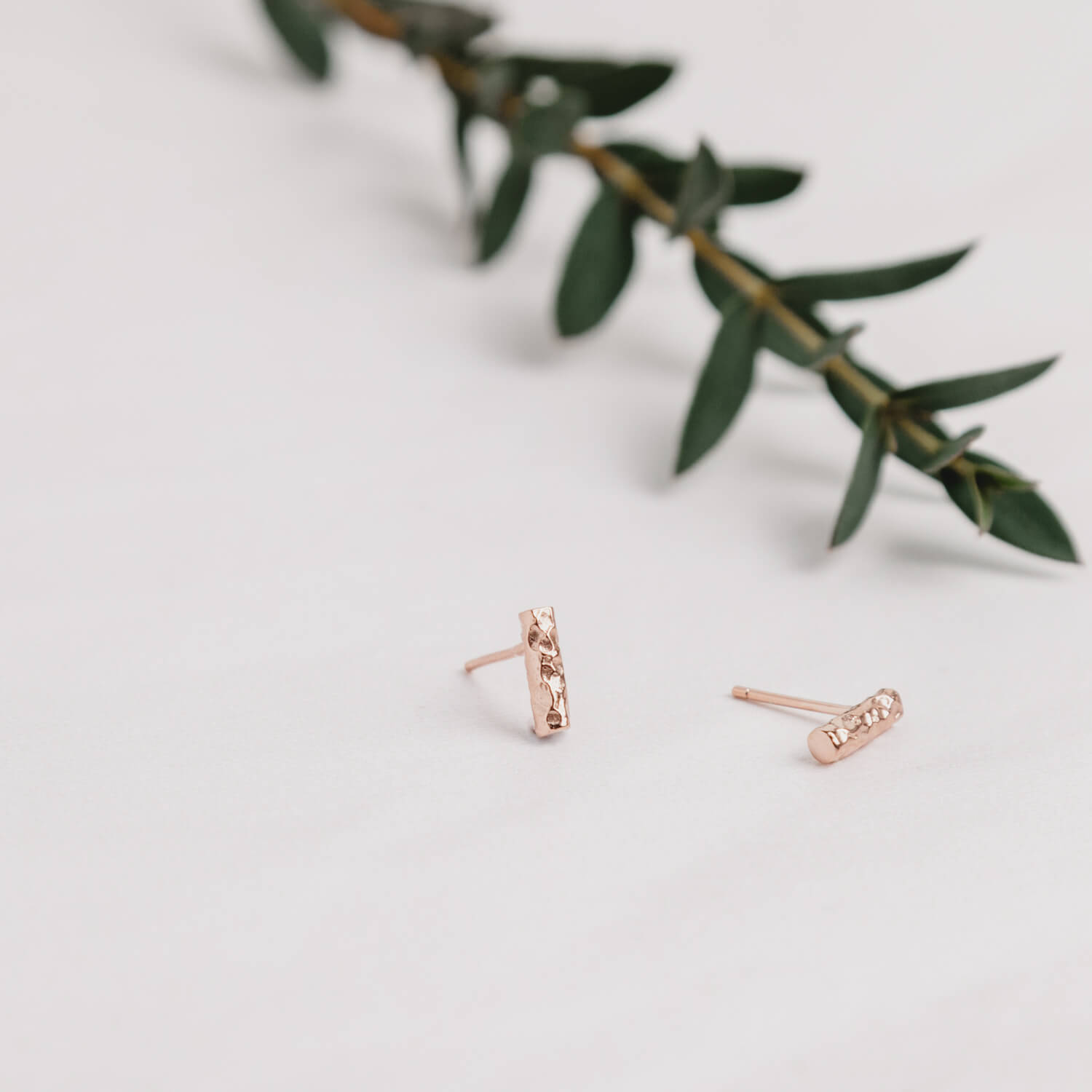 Close up of rose gold Small Bar Earrings with a meteorite style finish