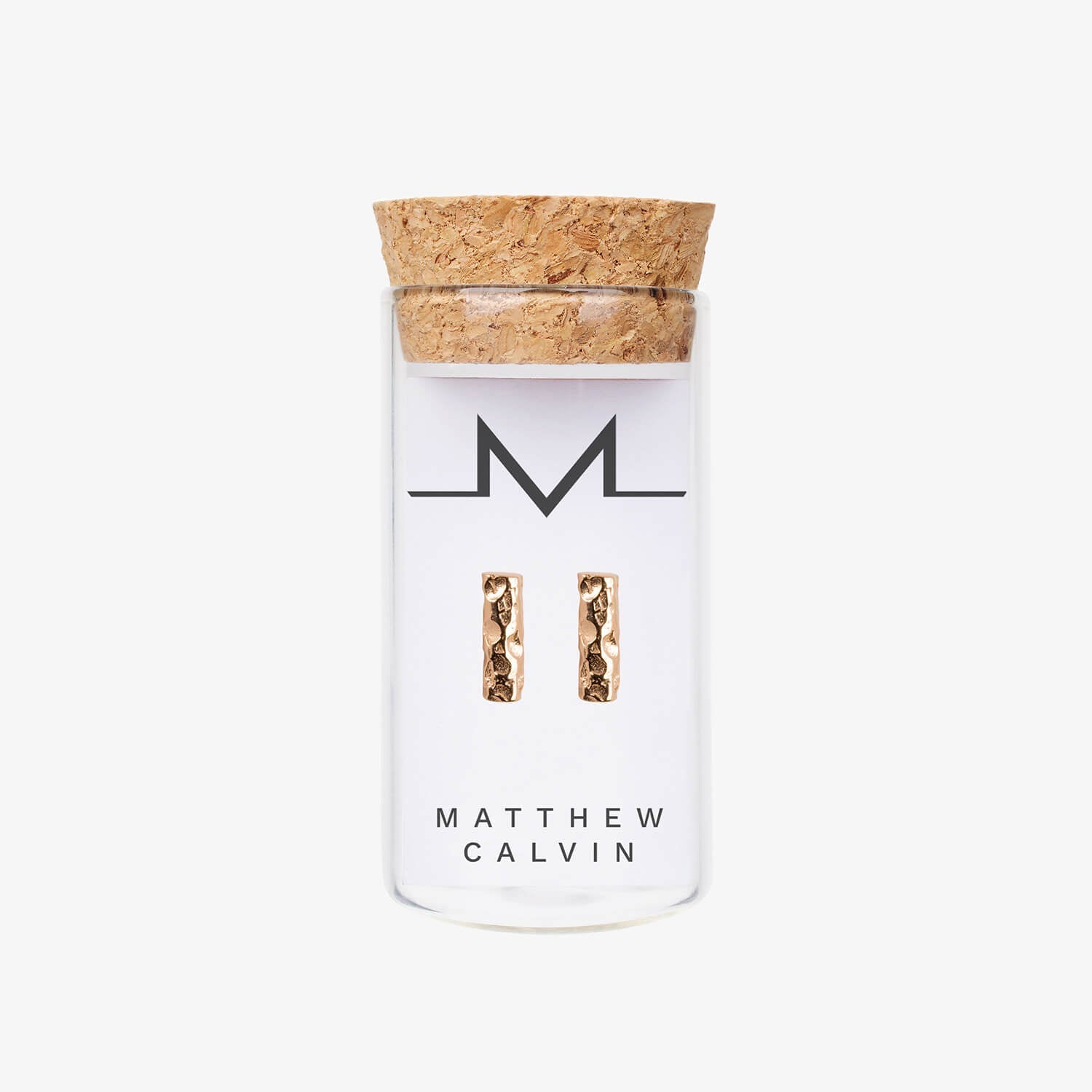 Small glass bottle with cork lid, holding Matthew Calvin Small Meteorite Bar Earrings in rose gold