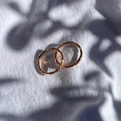 Two rose gold hand textured rings from Matthew Calvin's Meteorite collection photographed with shadows.