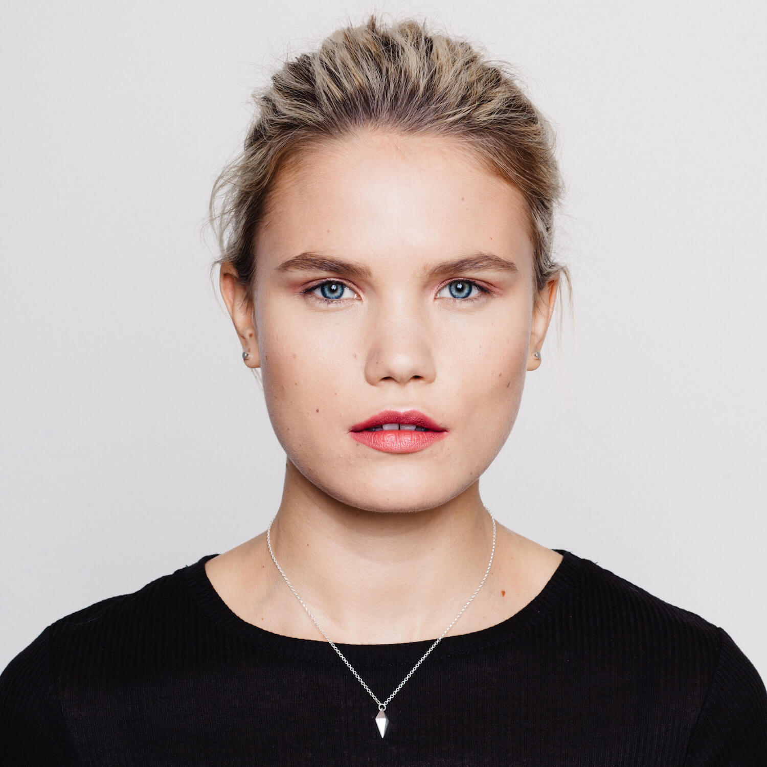 A model wearing a silver necklace with a kite shaped charm