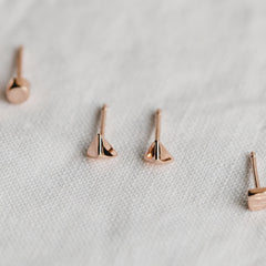 Close up of earrings with a geometric pyramid shape in rose gold