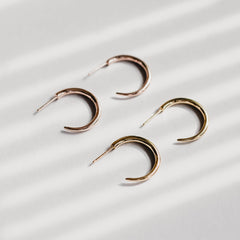 Close up of two pairs of hoops which are shaped like tusks, one pair is rose gold and one is gold