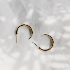 A close up of gold Tusk Hoop earrings