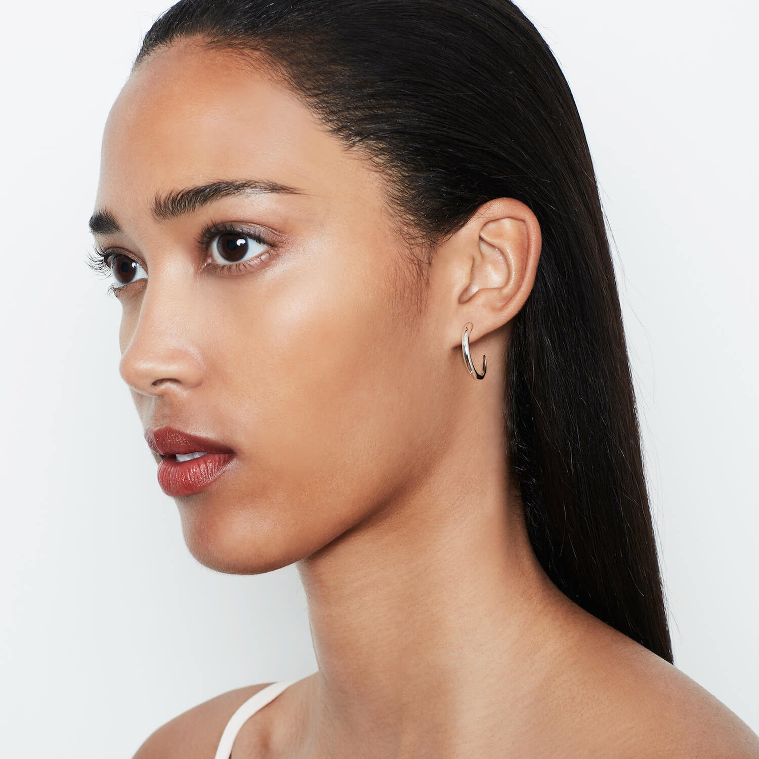 A model wearing silver Tusk Hoops earrings